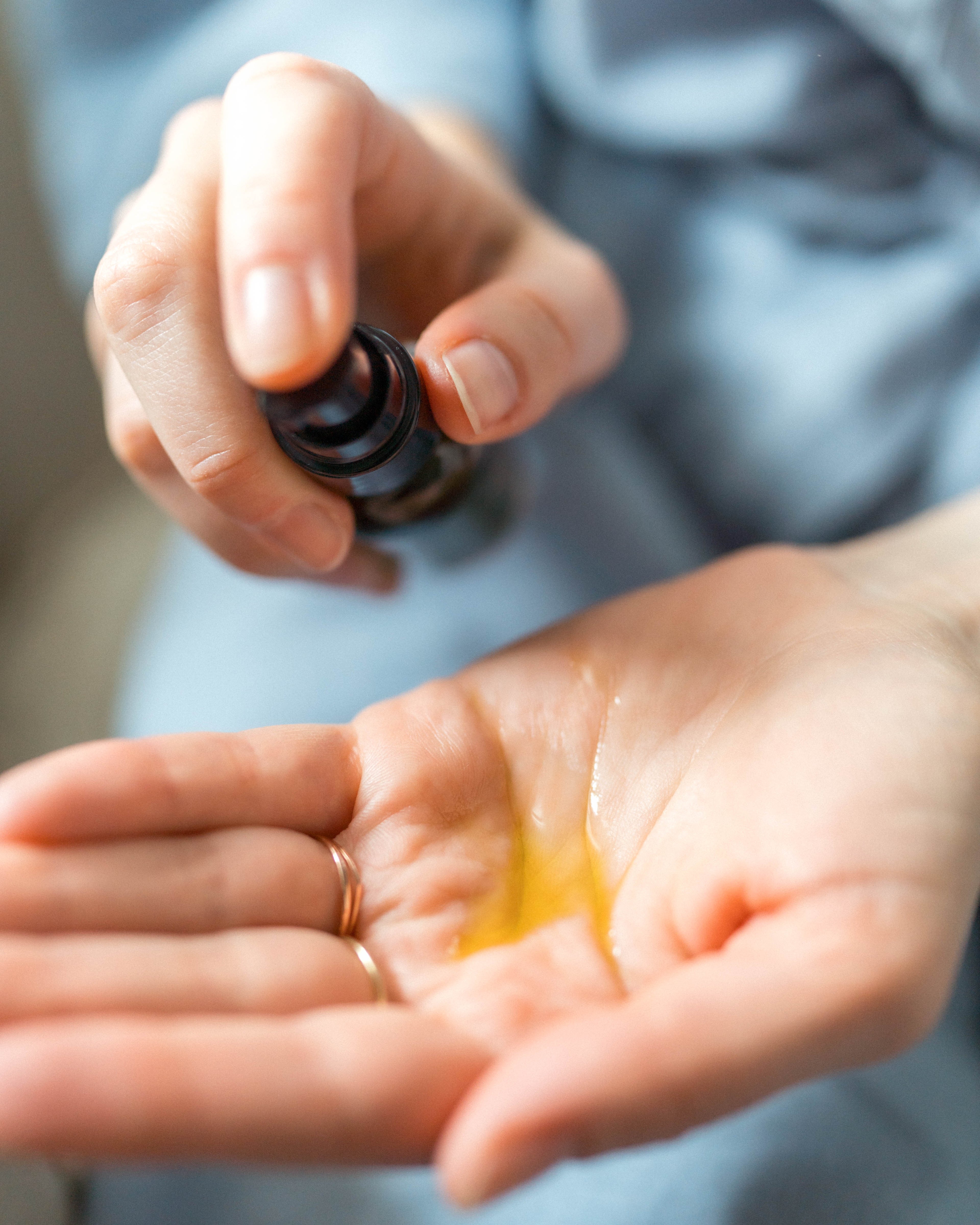 Person applying face oil from a small container into their palm