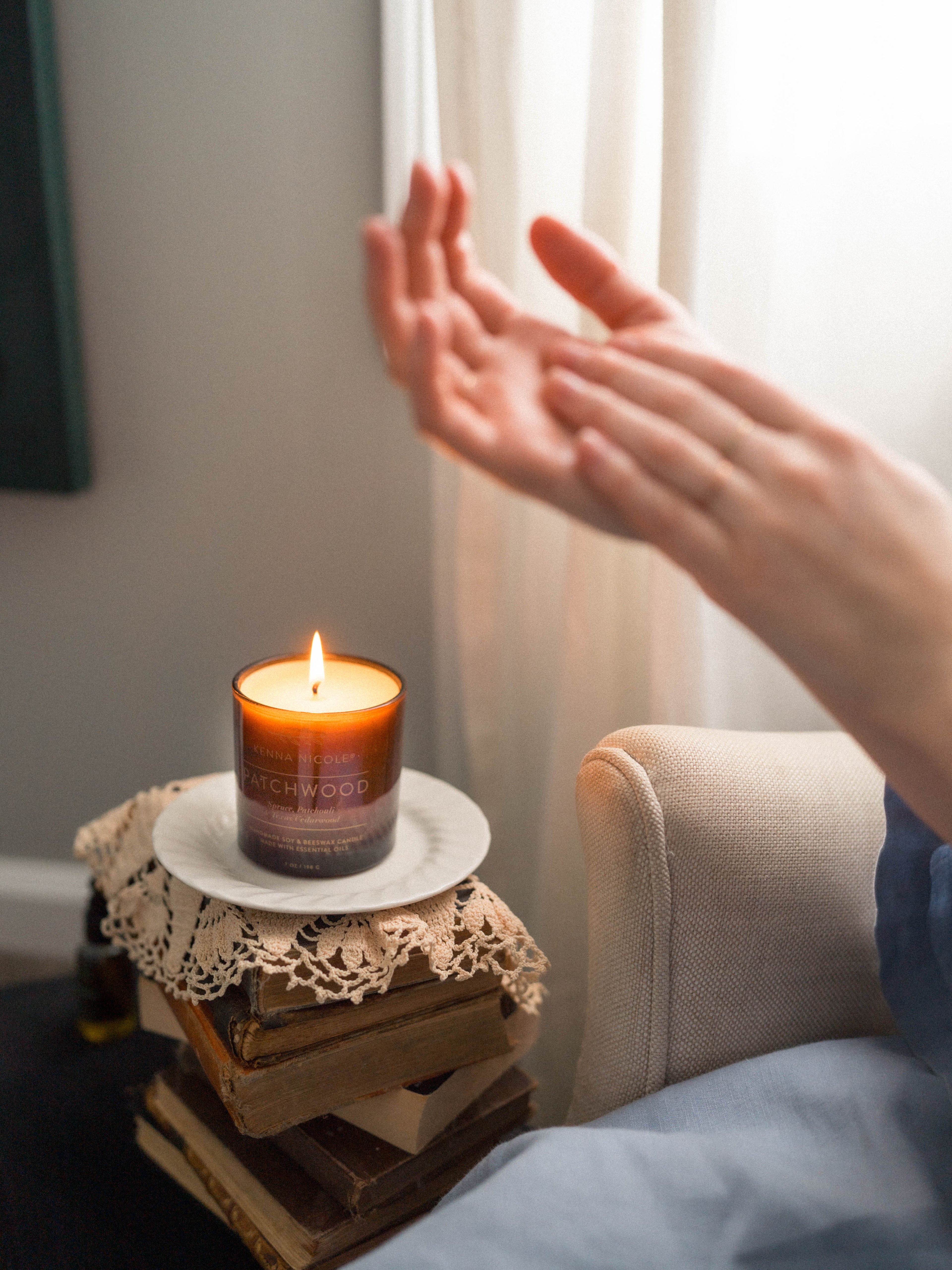 Patchwood Candle on a small wooden table next to a person's hand