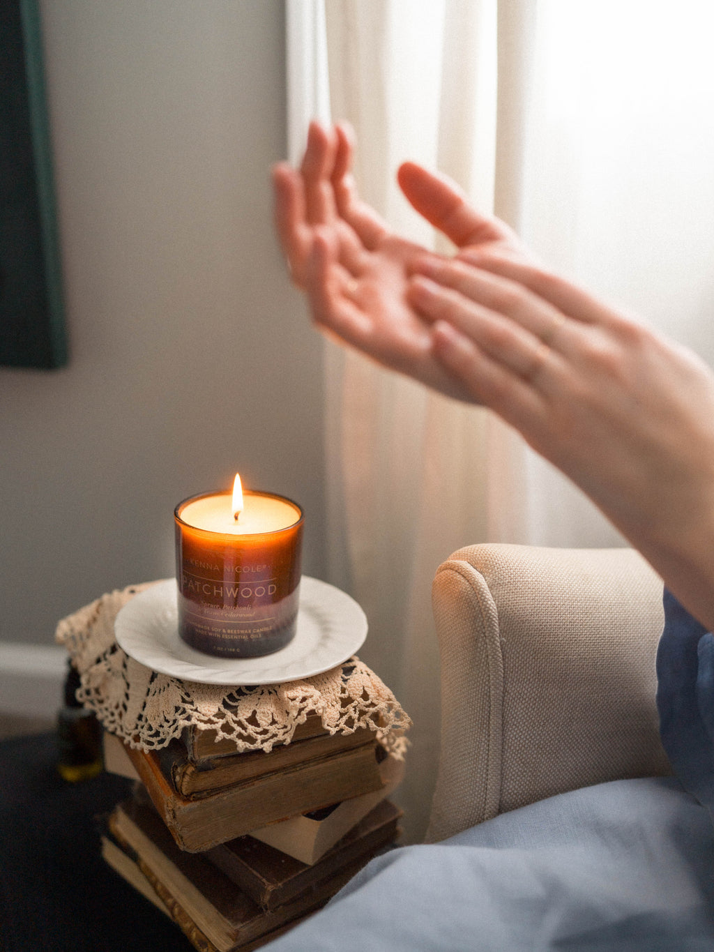 Patchwood Candle on a small wooden table next to a person's hand