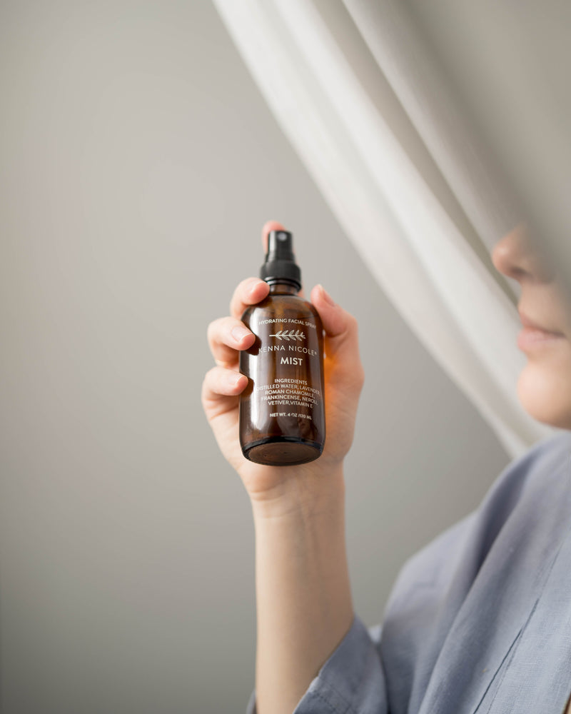 Person holding a bottle of Kenna Nicole mist spray against a neutral background