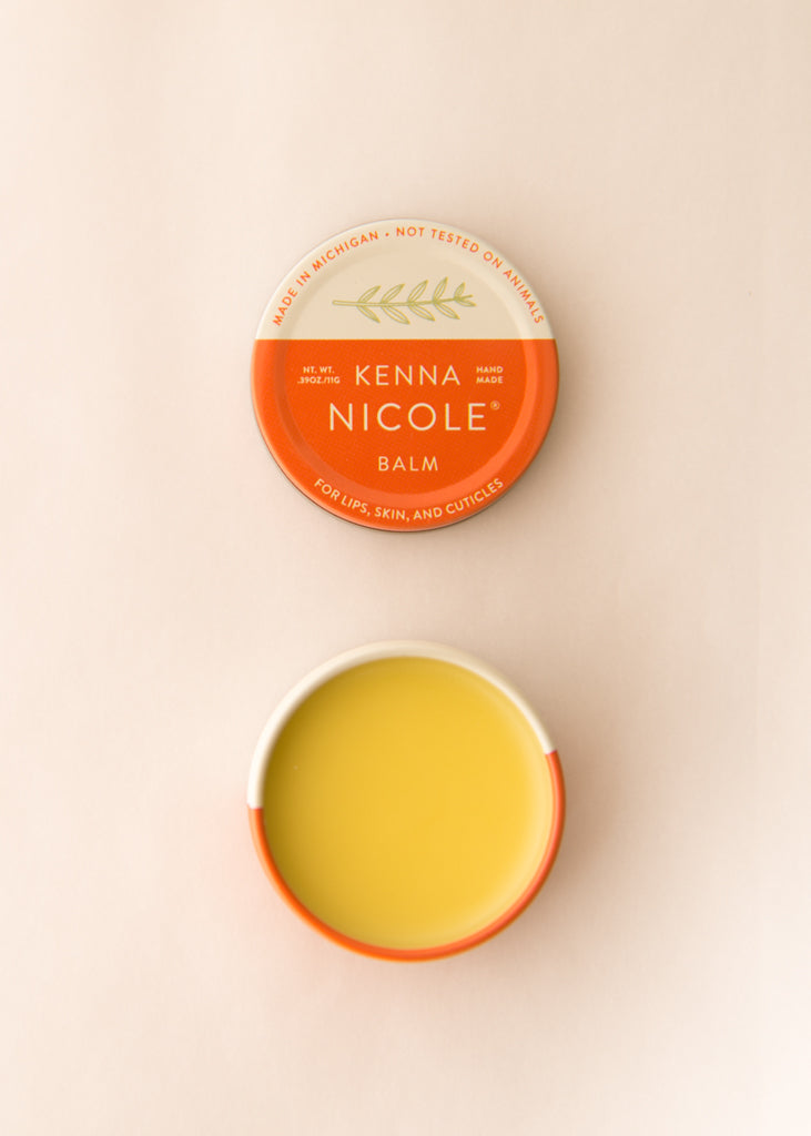 Kenna Nicole balm container with lid open on a beige background